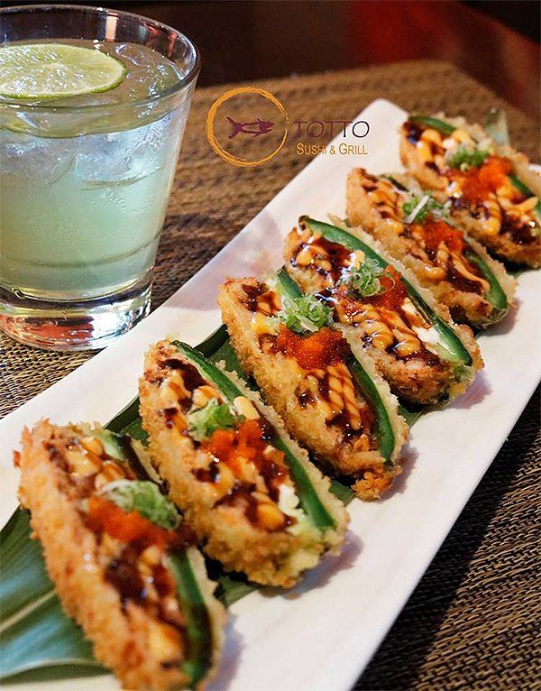 A white plate topped with fried jalapenos next to a drink