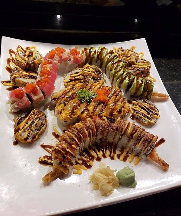 A white plate topped with a variety of sushi rolls.