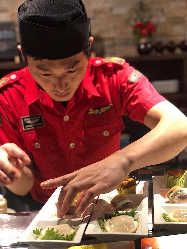 A man in a red uniform is preparing food on a table