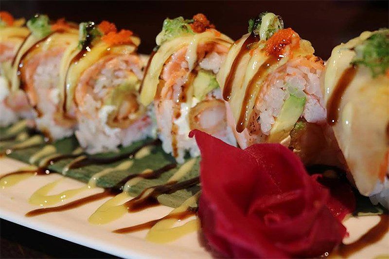 A white plate topped with sushi and a red flower.