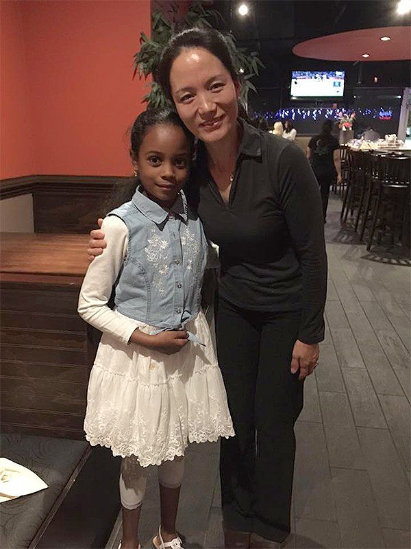 A woman is standing next to a little girl in a restaurant.