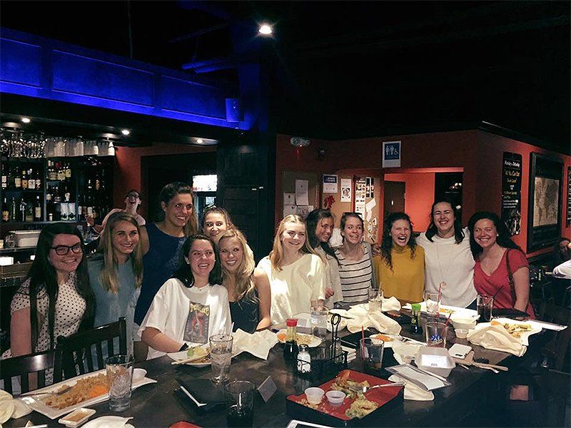 A group of women are posing for a picture at a table in a restaurant.