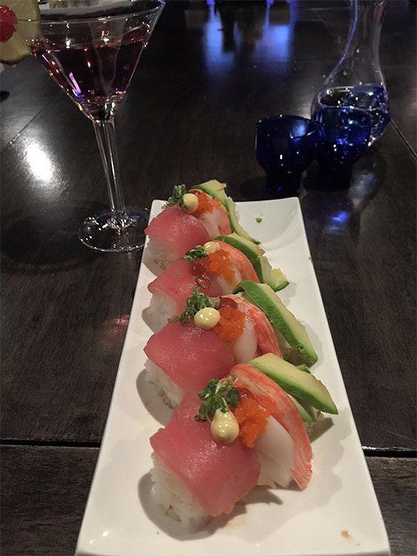 A white plate topped with sushi next to a martini glass