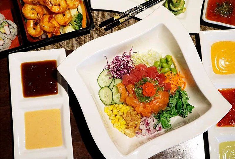 A bowl of food is sitting on a table next to a plate of shrimp.