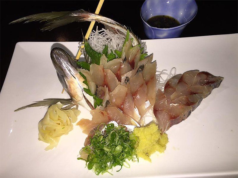 A white plate topped with sliced fish and vegetables