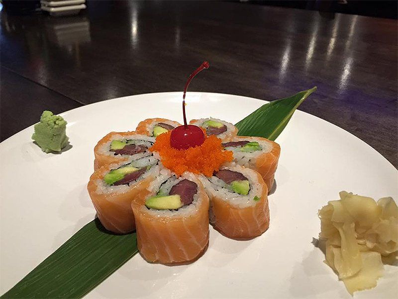 A plate of sushi with a cherry on top of it