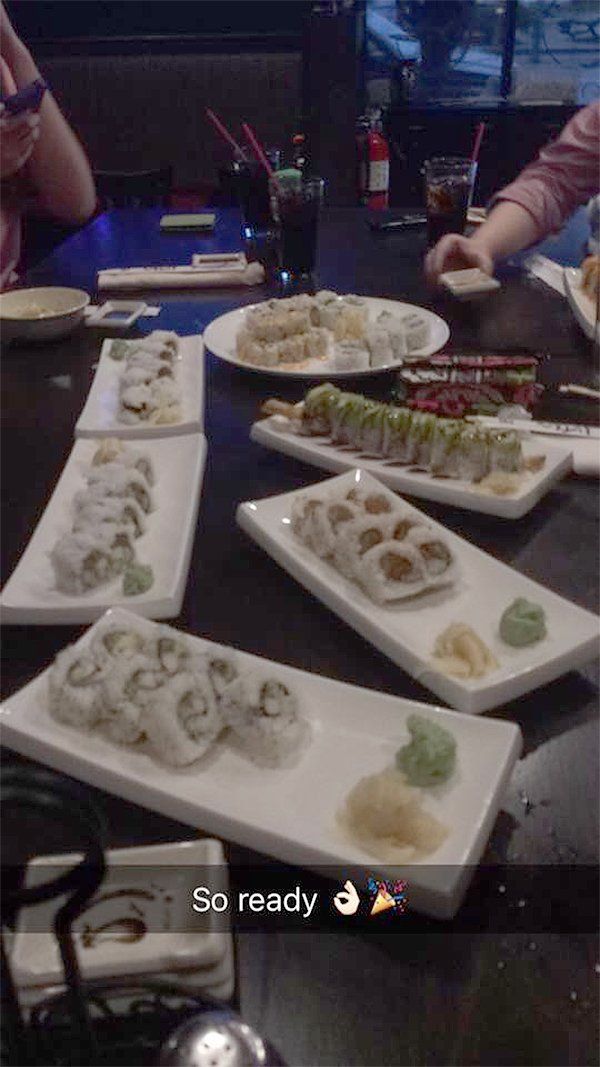 A person is sitting at a table with plates of sushi on it.