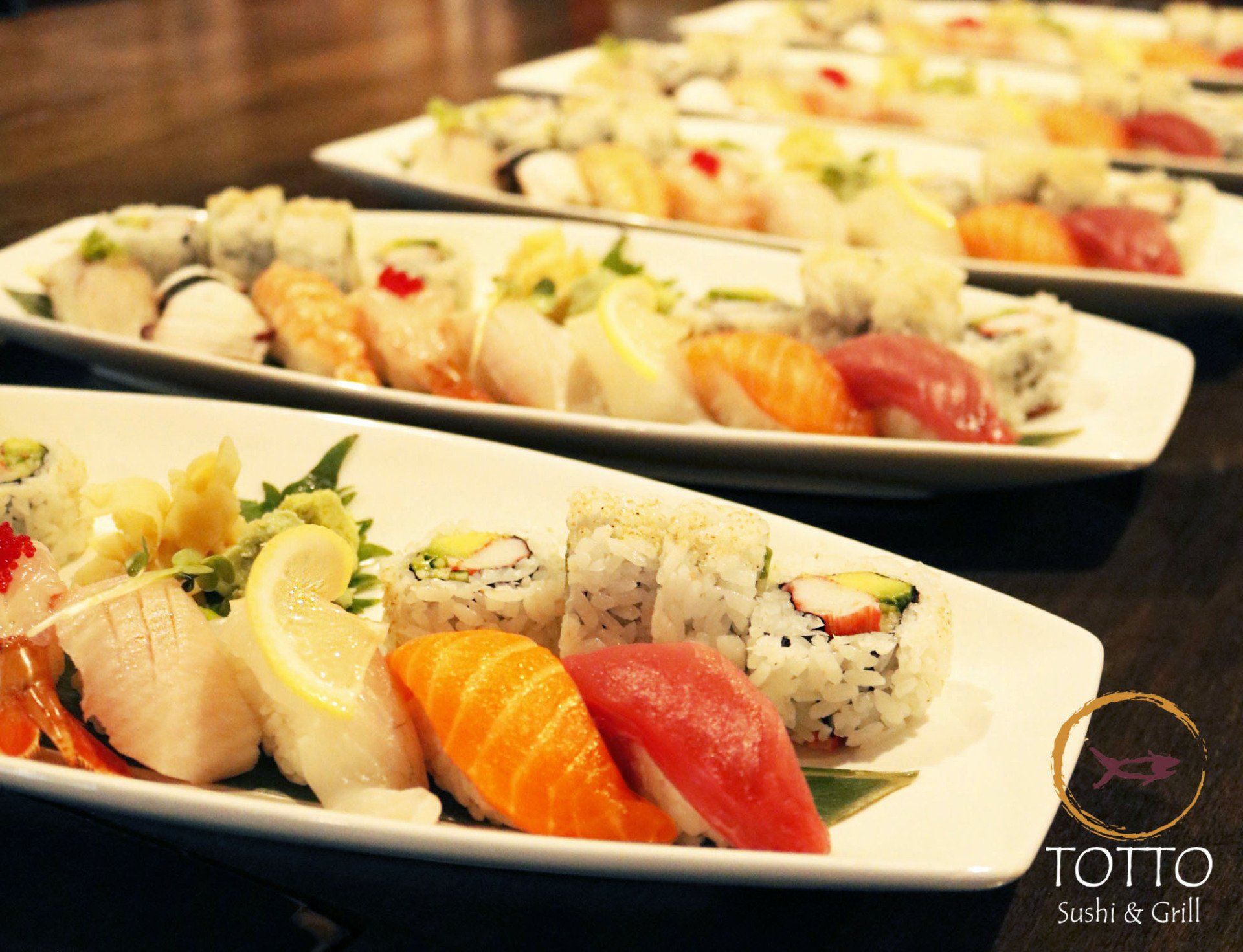 Several plates of sushi are lined up on a table at totto sushi & grill