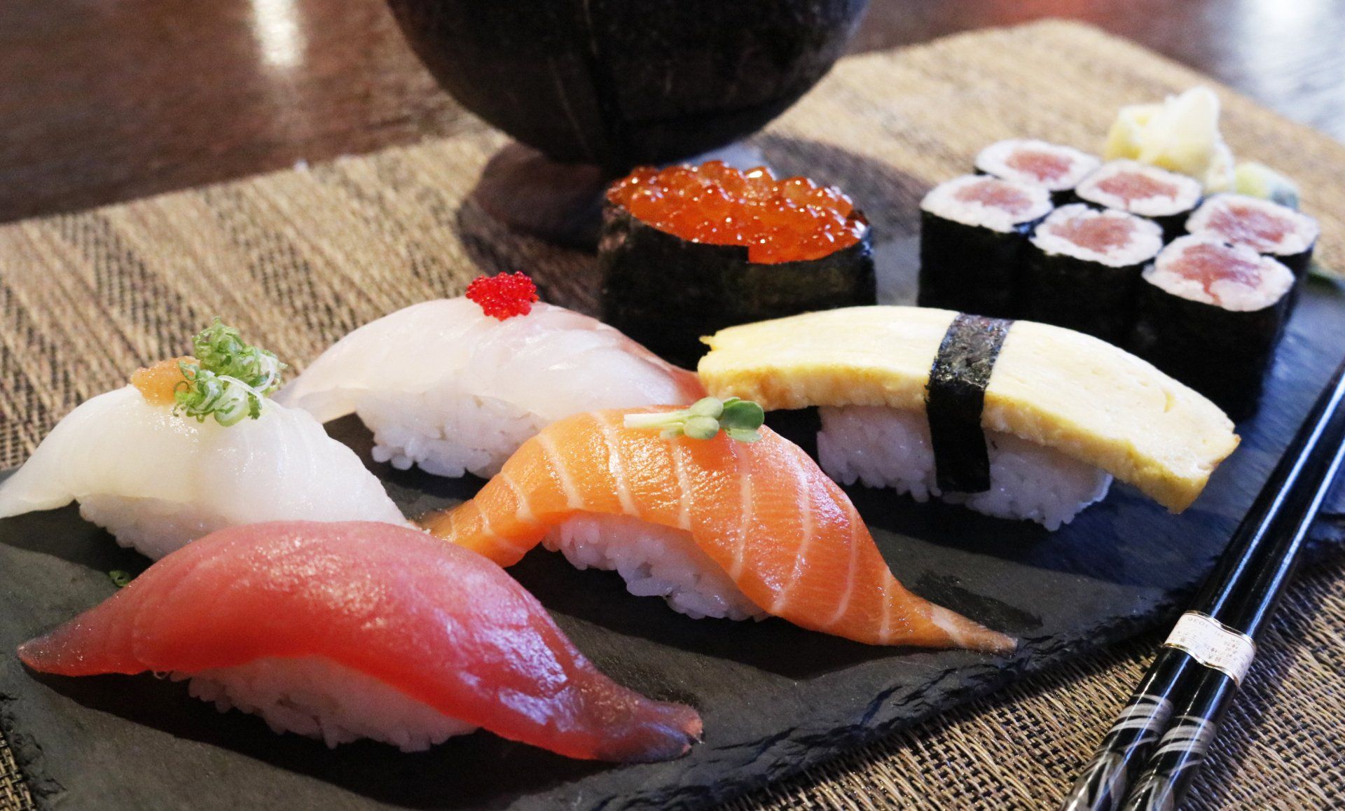 A plate of sushi with chopsticks on a table.