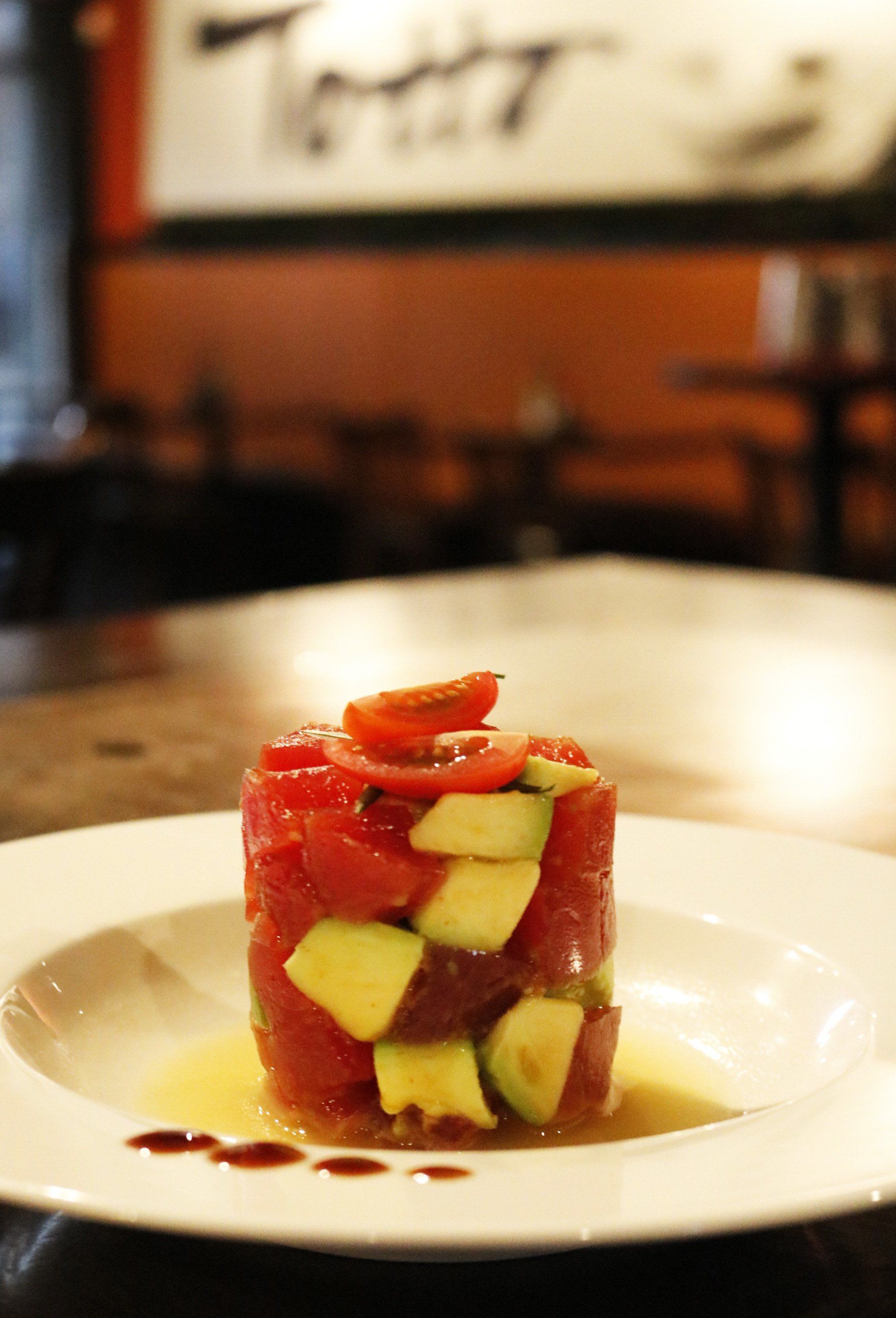 A white plate topped with a salad of tomatoes and avocados