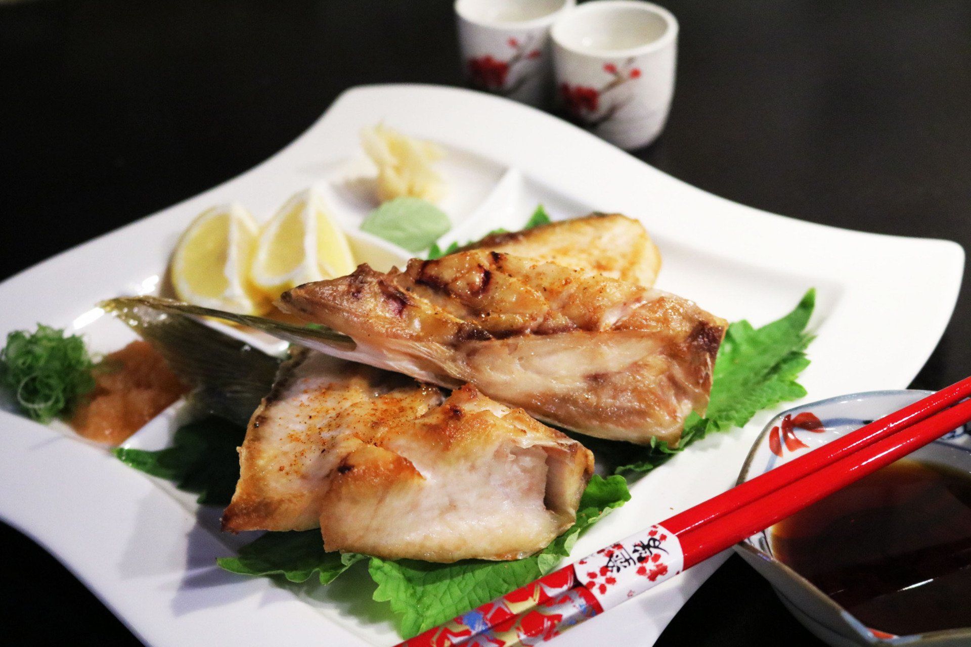 A plate of food with chopsticks and a bowl of dipping sauce