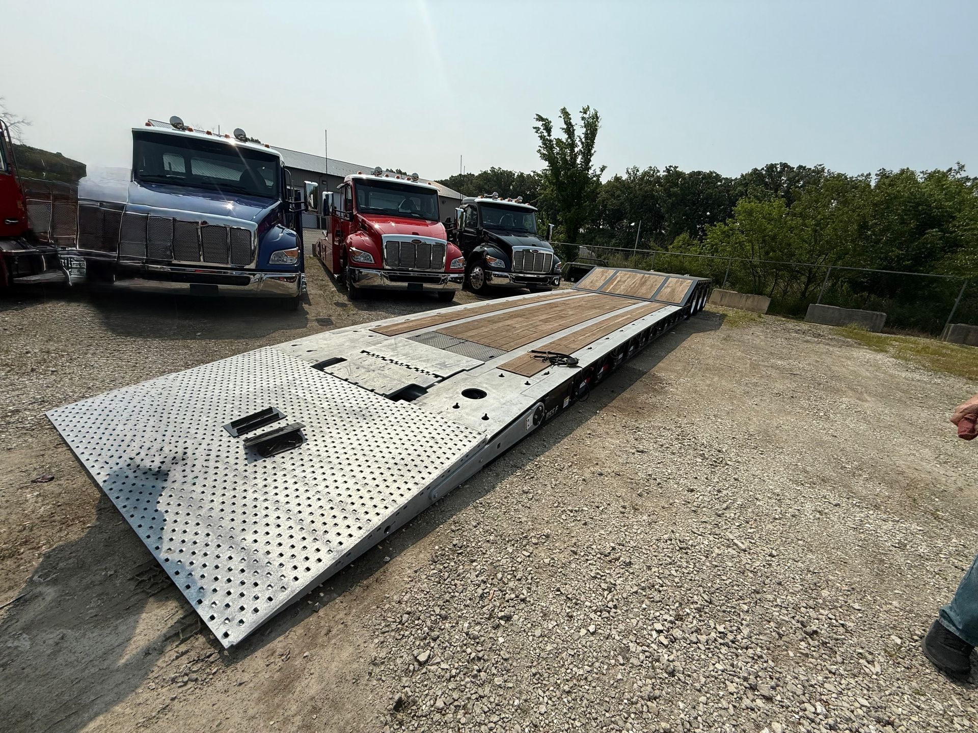 A row of trucks are parked in a gravel lot