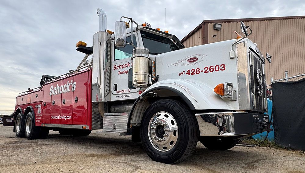 A red and white tow truck is parked in front of a building