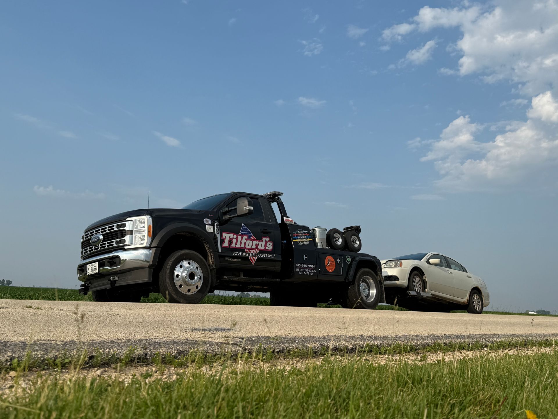 A tow truck is towing a car down a road.