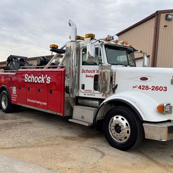 A red and white tow truck is parked in front of a building