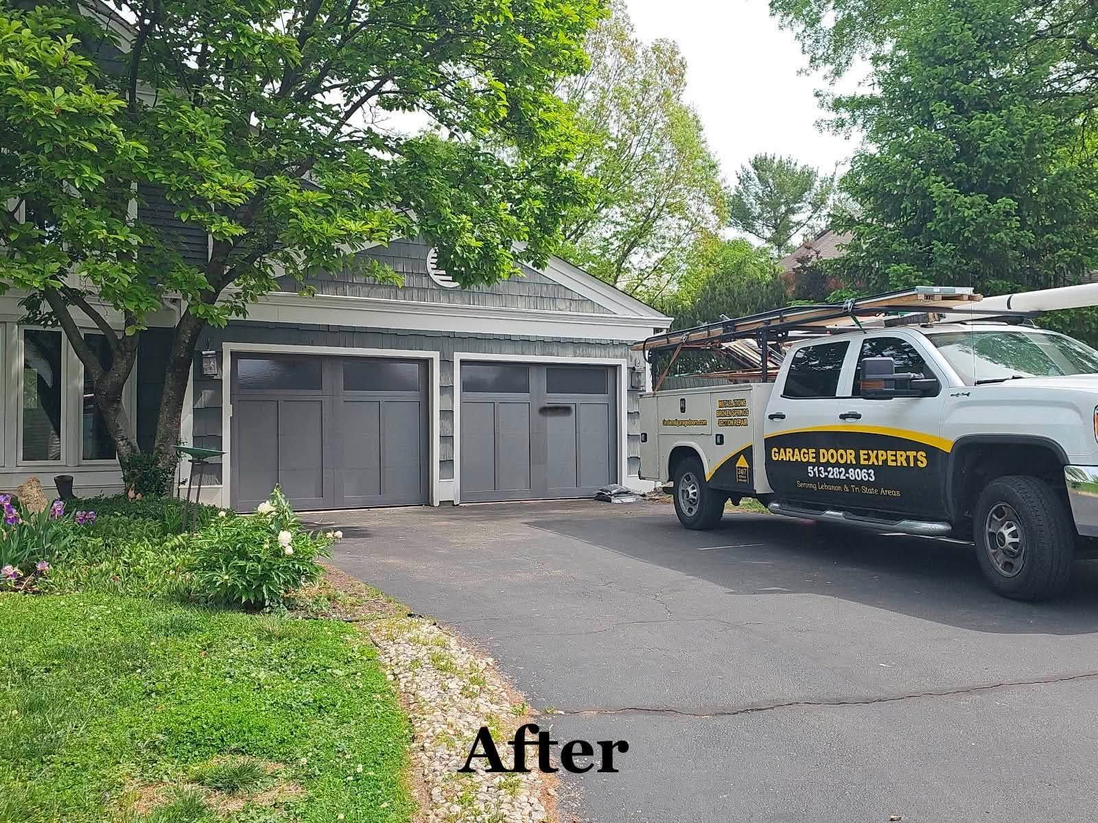 Driveway beside a garage with a white truck and black-and-yellow lettering parked in front.