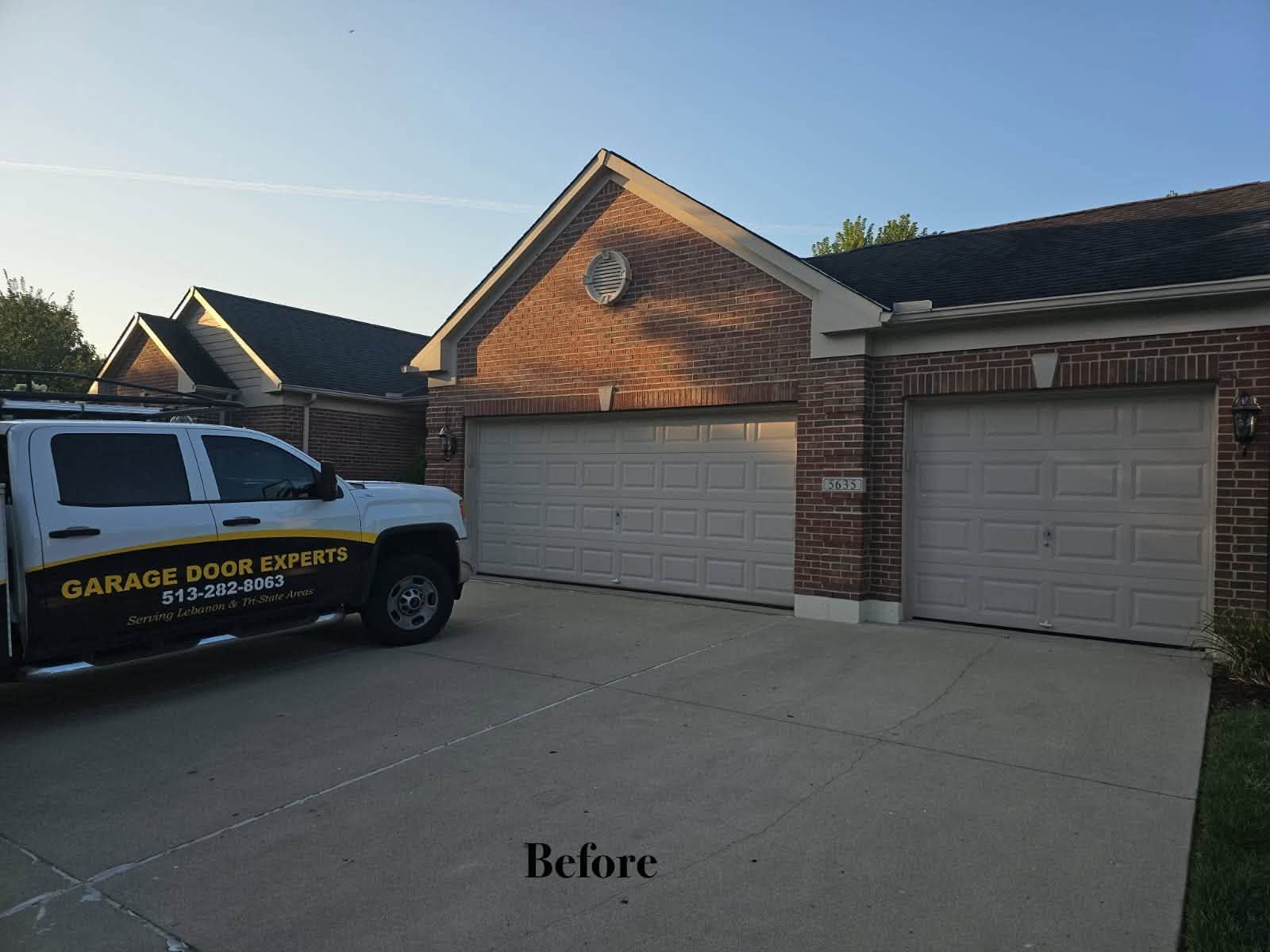 Driveway and brick garage before cleaning, with a work truck parked at left.