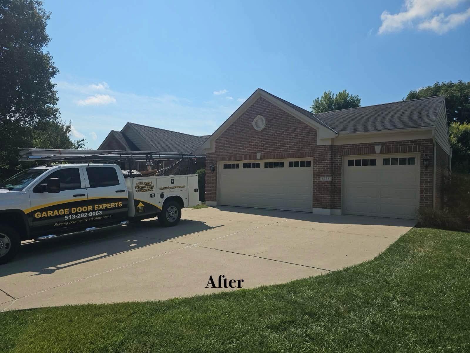 Suburban brick house with two garage doors and a work truck parked in the driveway.