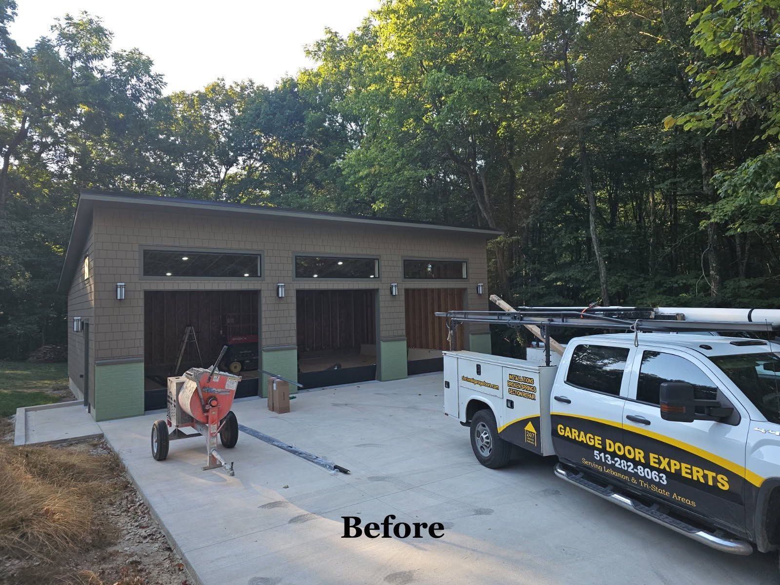 Before photo of a garage with construction tools and a service truck in front, surrounded by trees