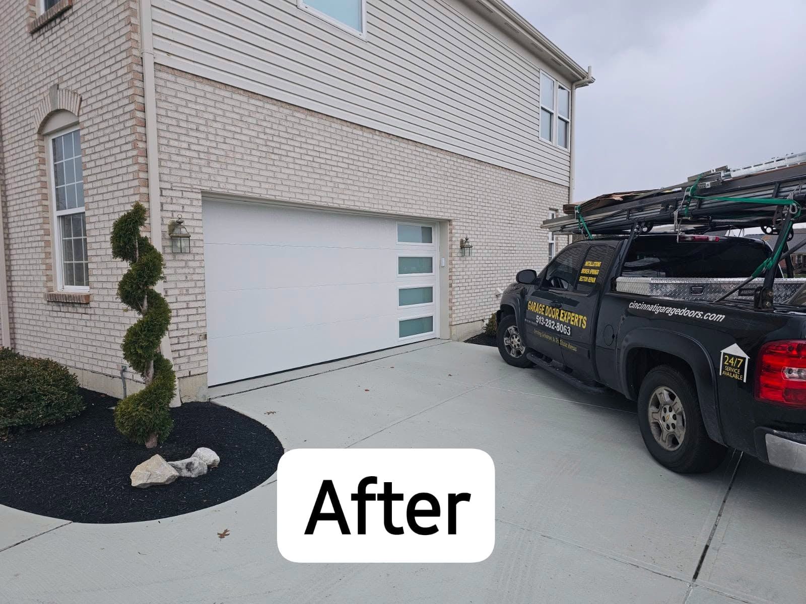 After photo of a beige brick house garage with a black work truck parked in the driveway