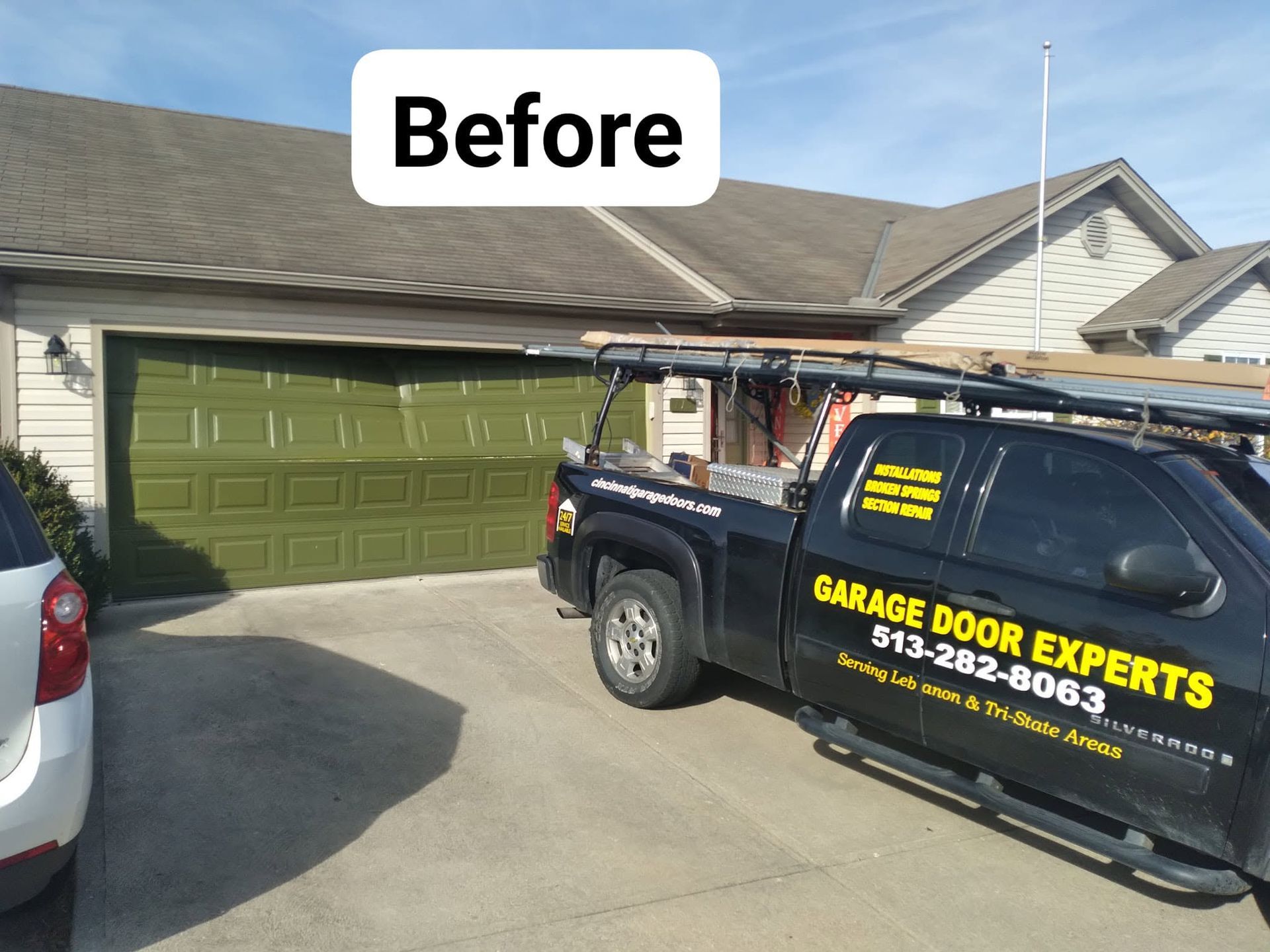 Garage door before repair at a suburban home, with a work truck parked in the driveway.