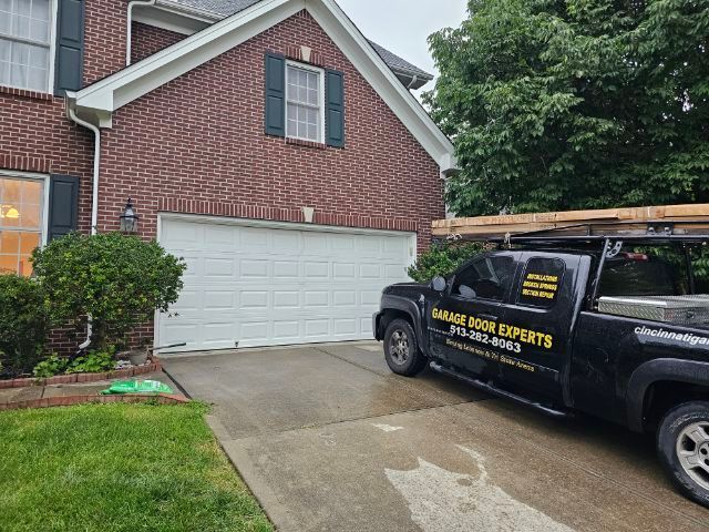 Brick house driveway with a white garage and a black service truck parked outside