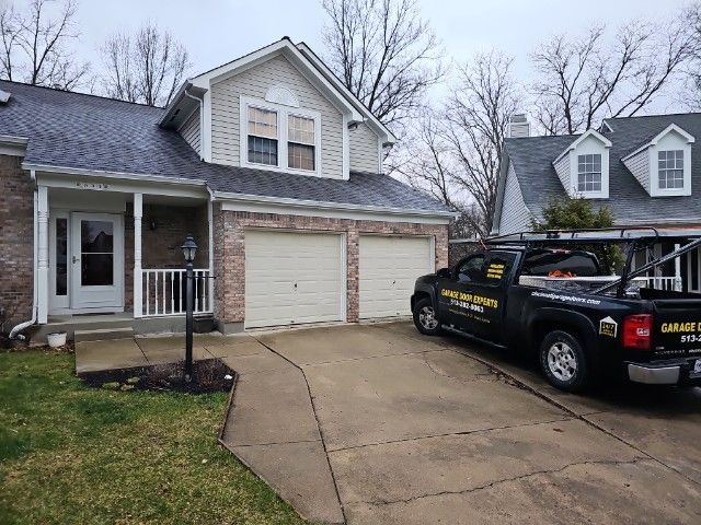 Suburban house with double garage, driveway, and black pickup truck under an overcast sky