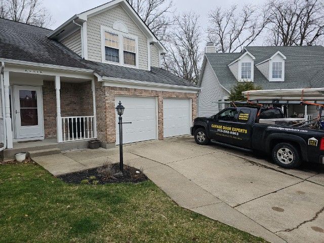 Suburban house with two garage doors, a driveway, and a black service truck parked outside