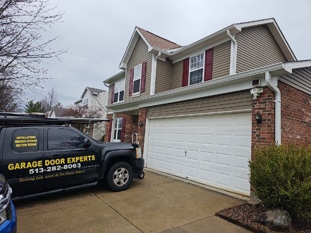 Garage Door Experts service truck parked in front of a suburban house with a white garage door.