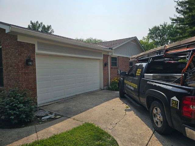 Suburban driveway with white garage door and black work truck parked outside گھر
