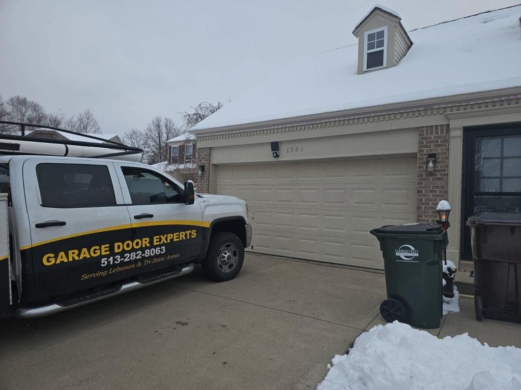 Garage door repair van parked in front of a snow-covered suburban house garage.