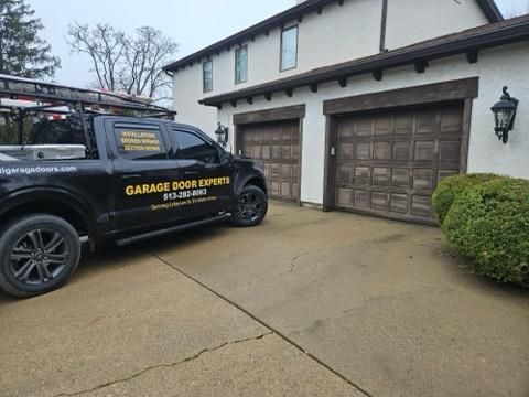 Garage Door Experts service van parked in a driveway beside a suburban garage.
