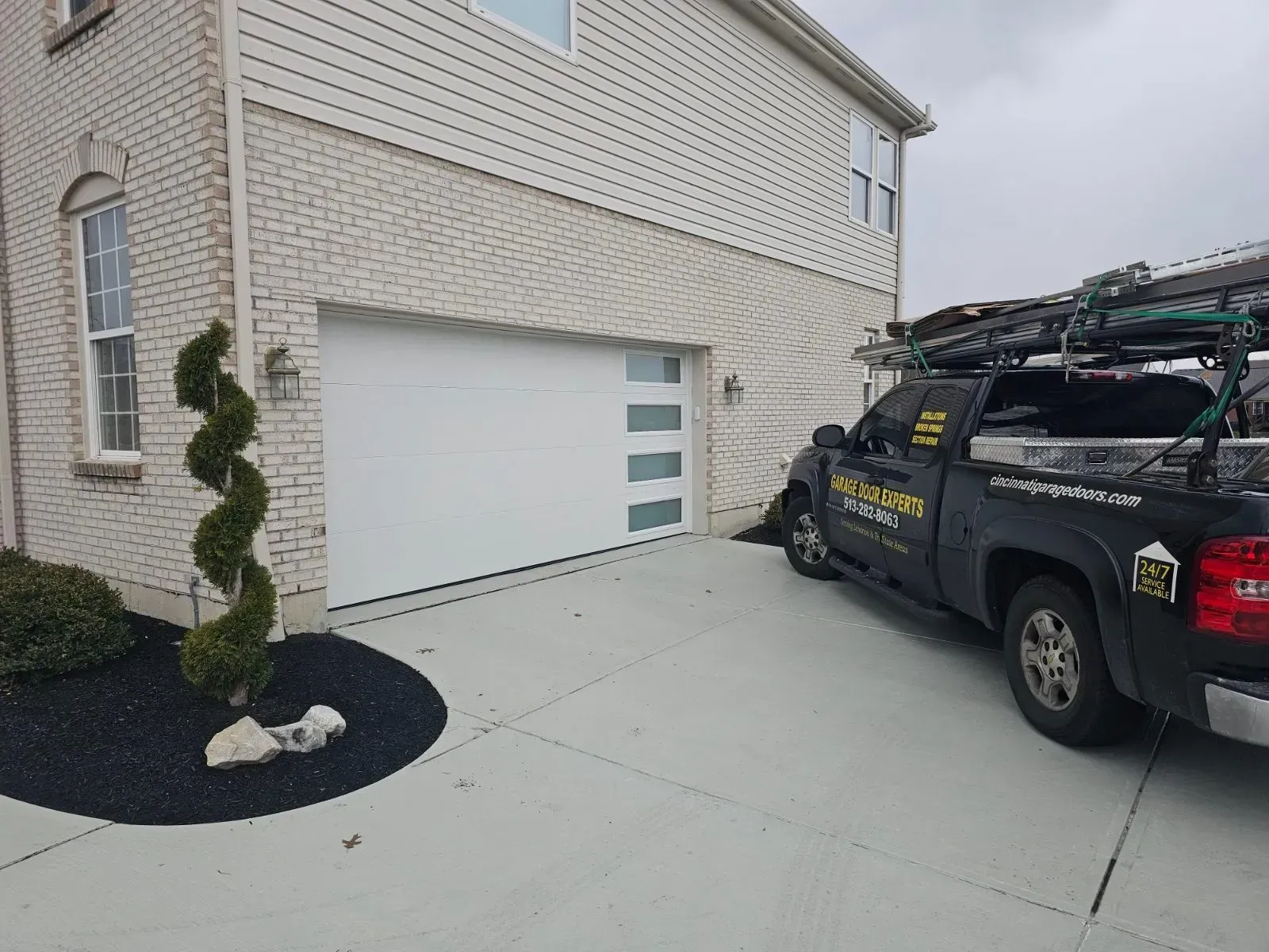 White garage door on a beige house with a black work truck parked in the driveway