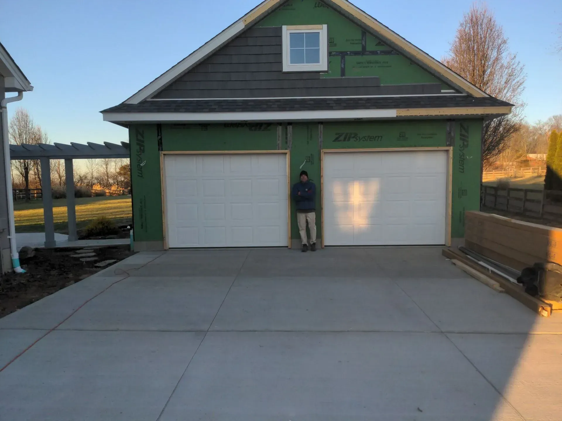 House with a two-car garage and a person standing in the driveway.