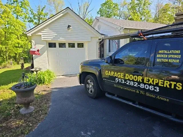 Garage Door Experts truck parked beside a white garage in a sunny driveway