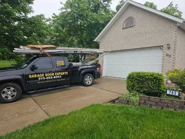 Garage Door Experts service truck parked in a driveway beside a suburban house.