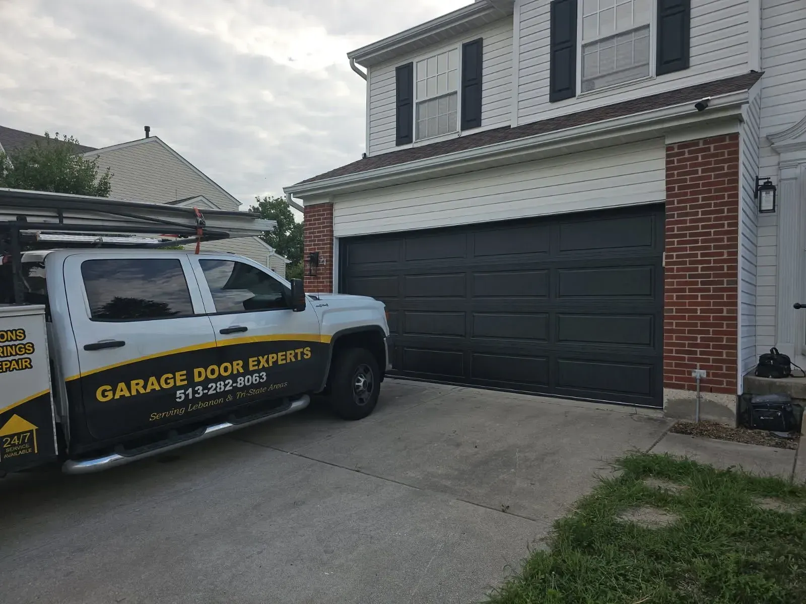 Truck parked in front of a two-car garage with a garage door repair sign on the side