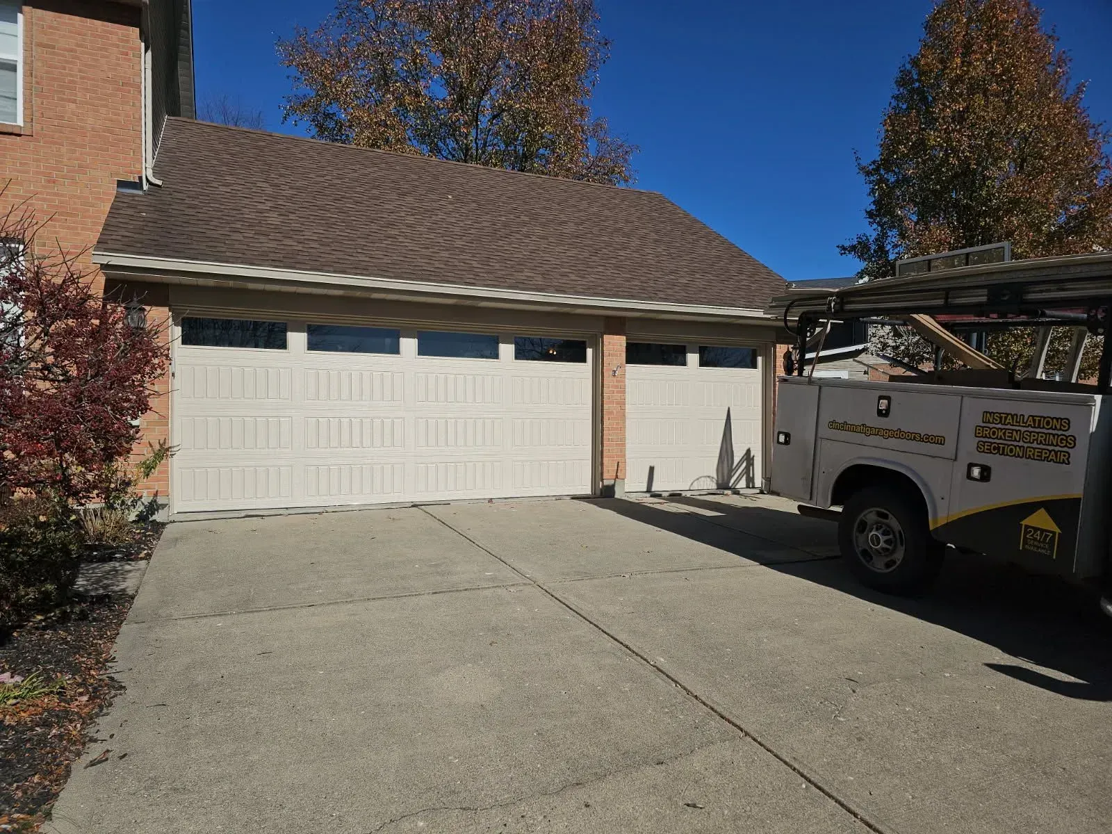 Suburban house with two-car garage and a work truck parked in the driveway under a clear blue sky
