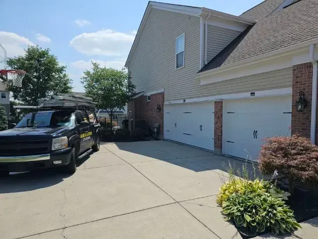 Driveway beside suburban townhouse garages with a black pickup truck parked on the left
