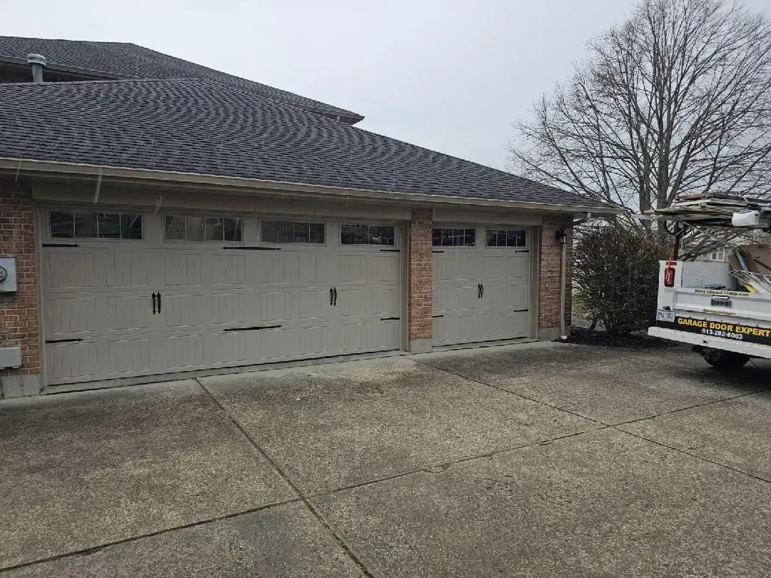 Suburban two-car garage with a dark shingled roof and a utility truck parked beside it.