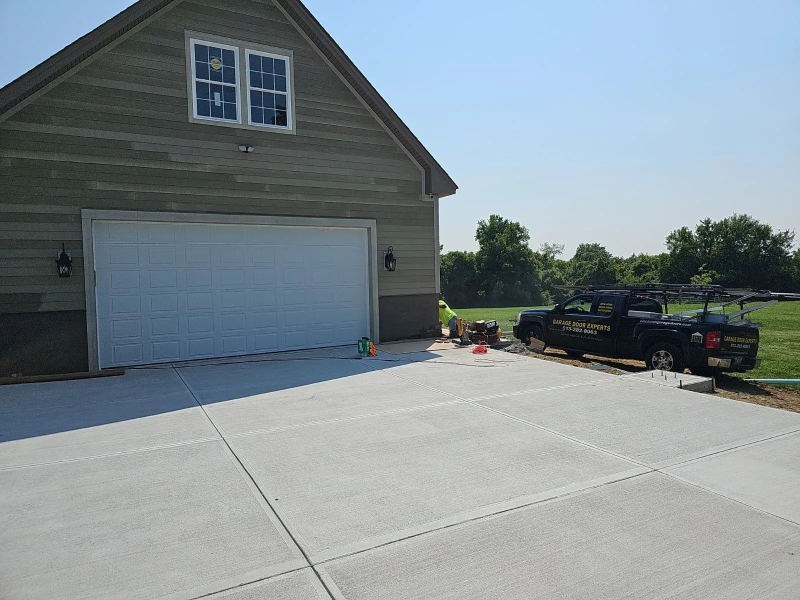 Driveway in front of a two-car garage with a pickup truck and cones near the right side.