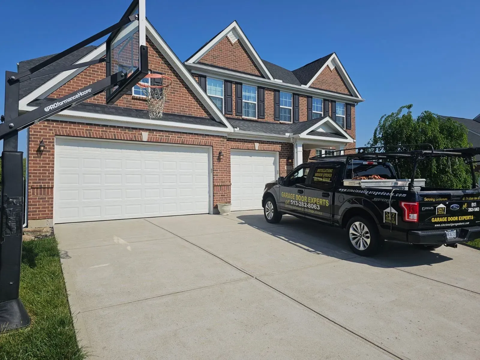 Suburban brick house with a three-car garage and a black pickup truck parked in the driveway