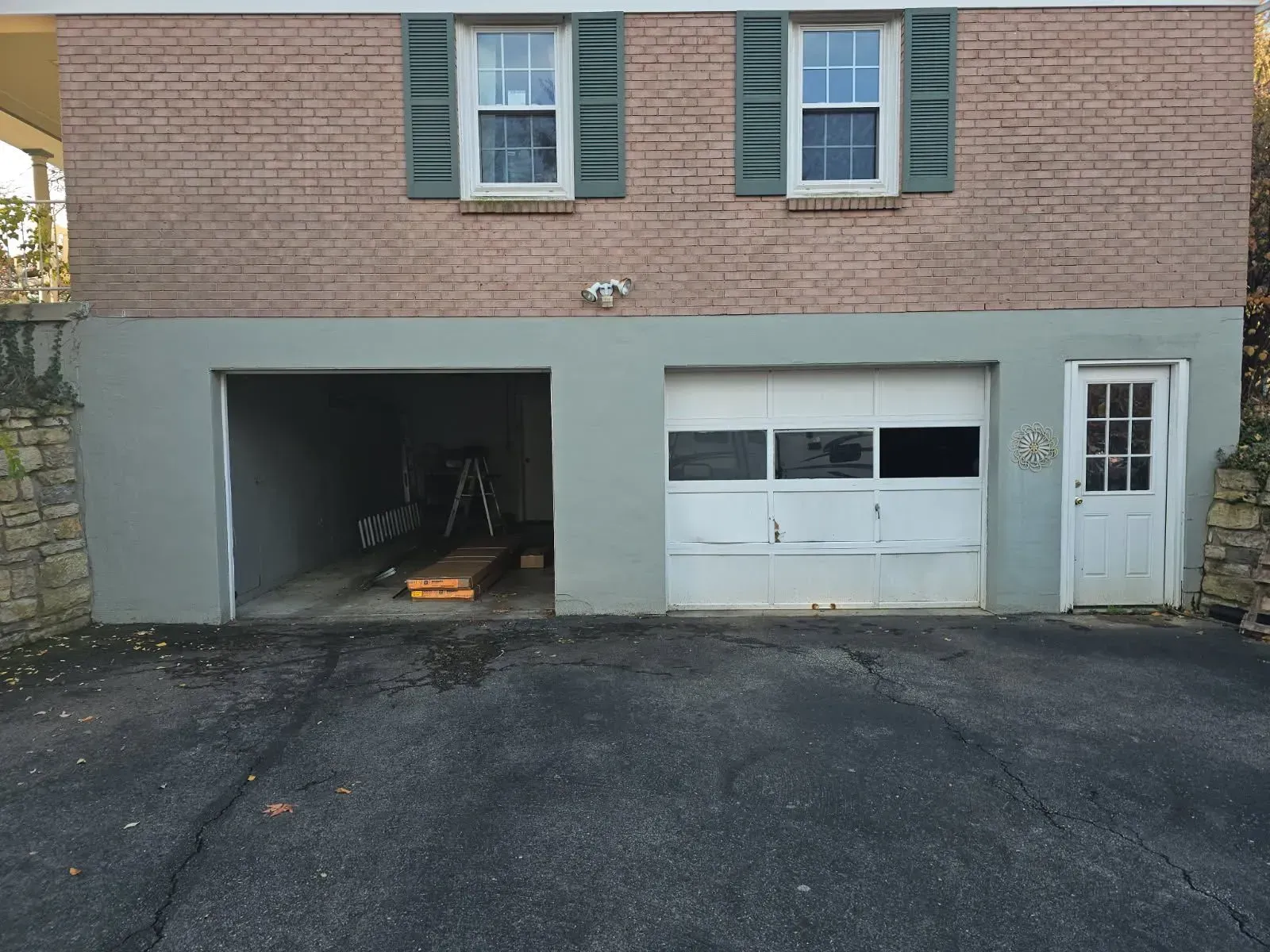 Two-car garage with a closed white door and an open bay under a brick house facade