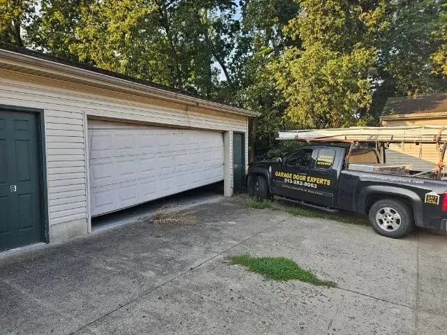 Black pickup truck parked beside a white garage in a driveway