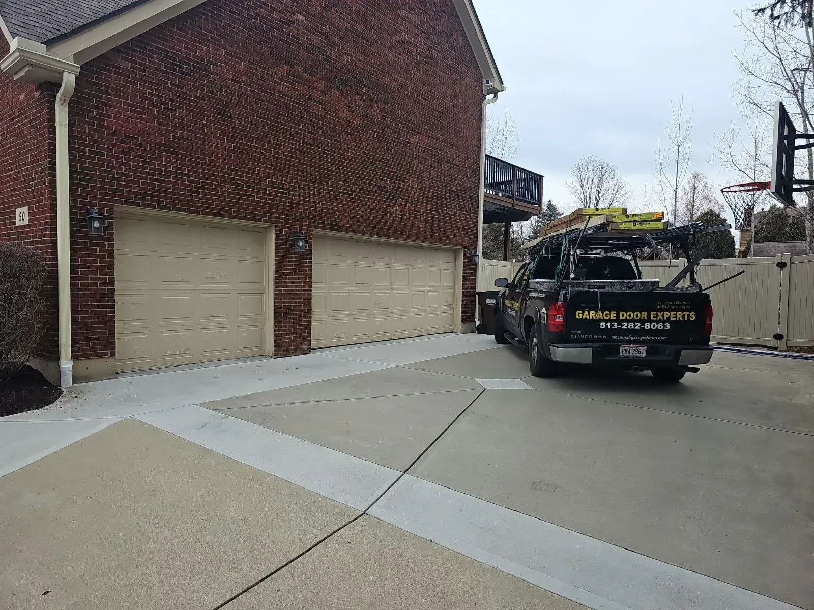 Brick suburban house with two garage doors and a utility truck parked in the driveway