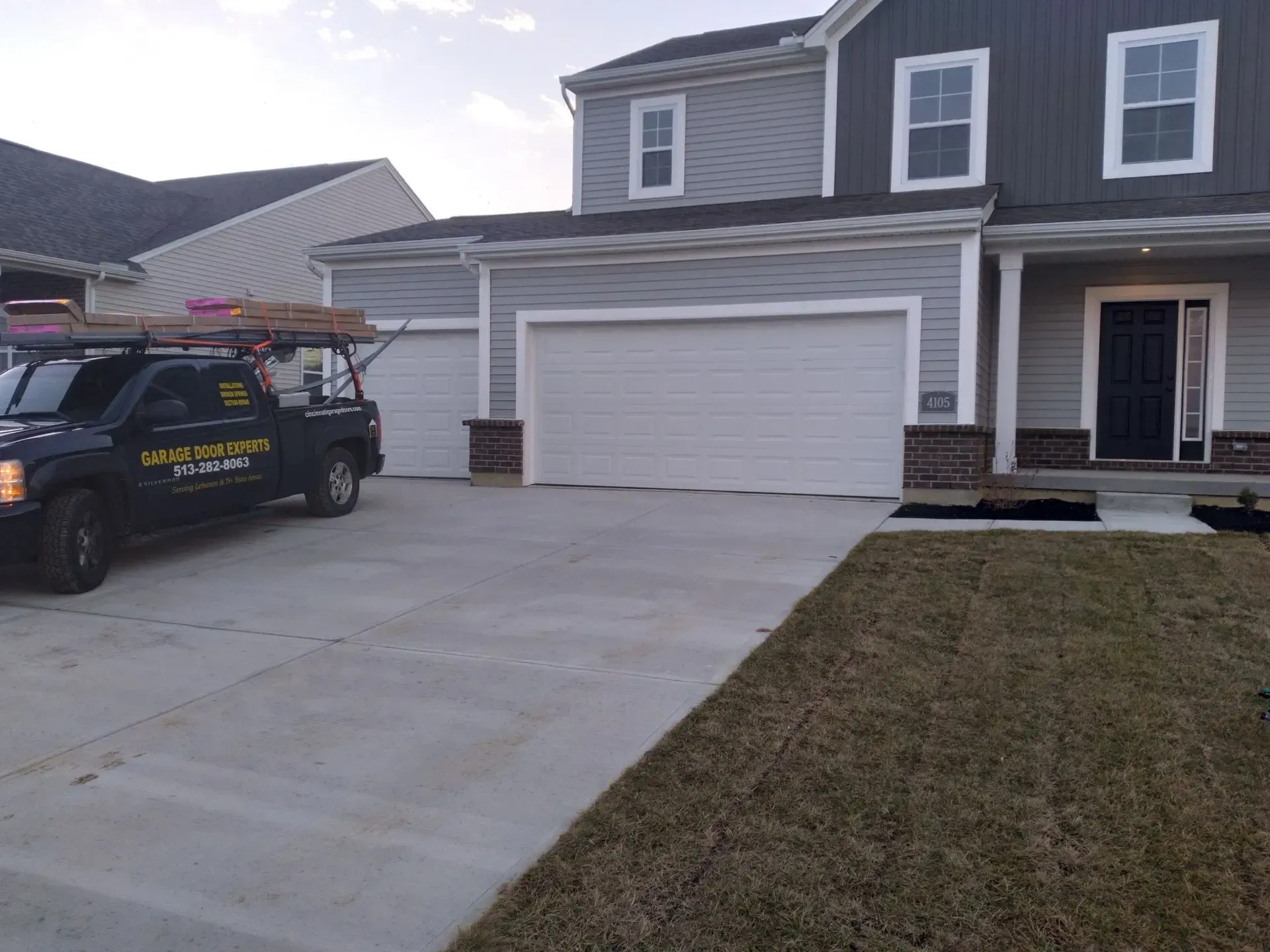 Suburban house with a two-car garage and a work truck parked in the driveway.