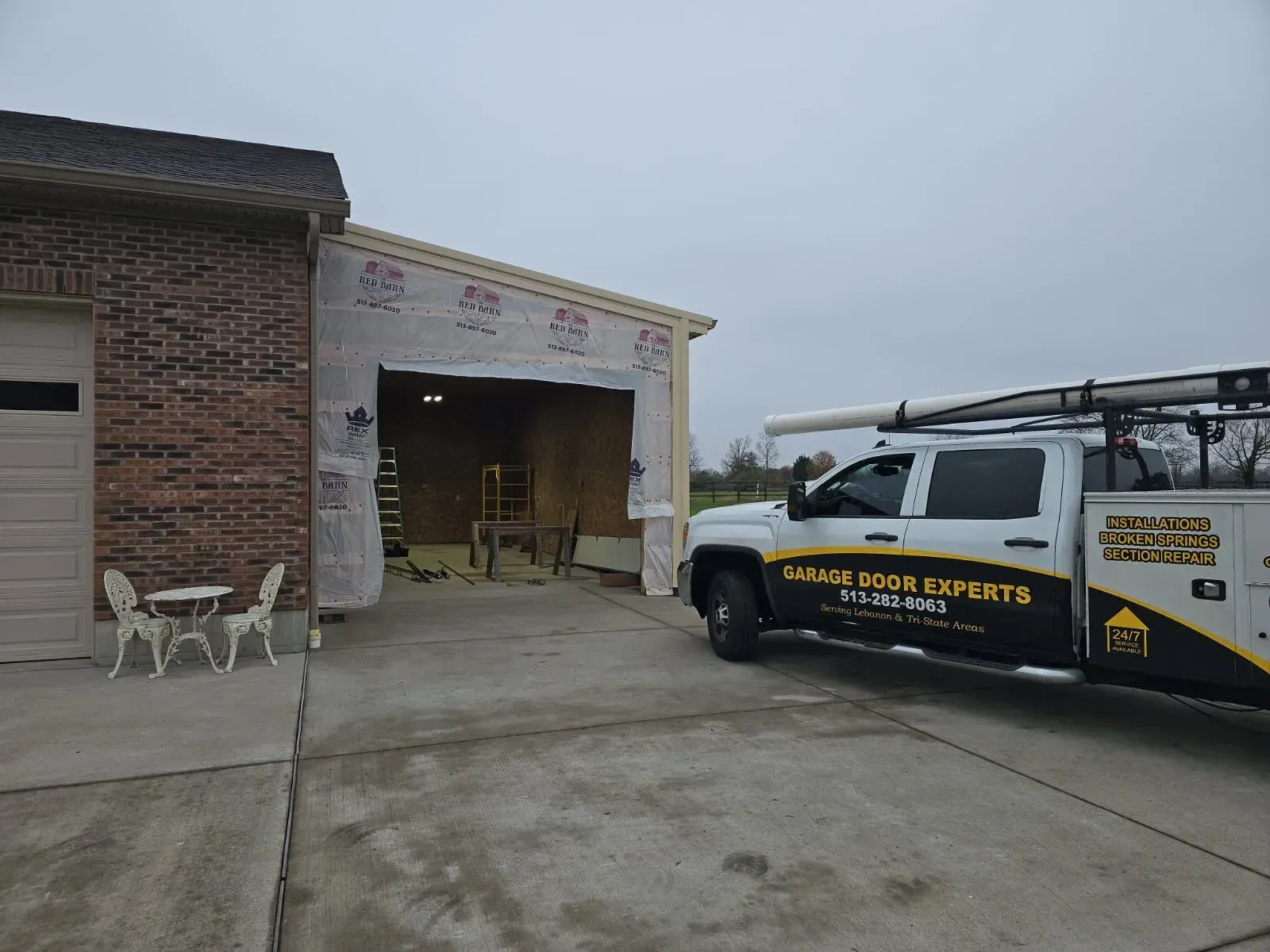 Brick garage with open bay and a service truck parked beside it on a driveway.