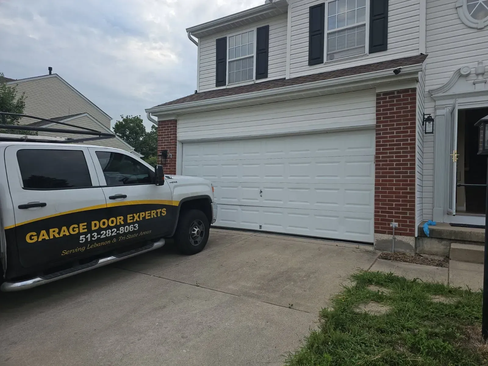 White garage door under construction beside a Garage Door Experts van in a suburban driveway