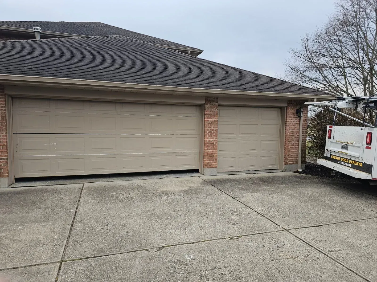 Suburban brick house with a beige two-car garage and a white work van parked in the driveway