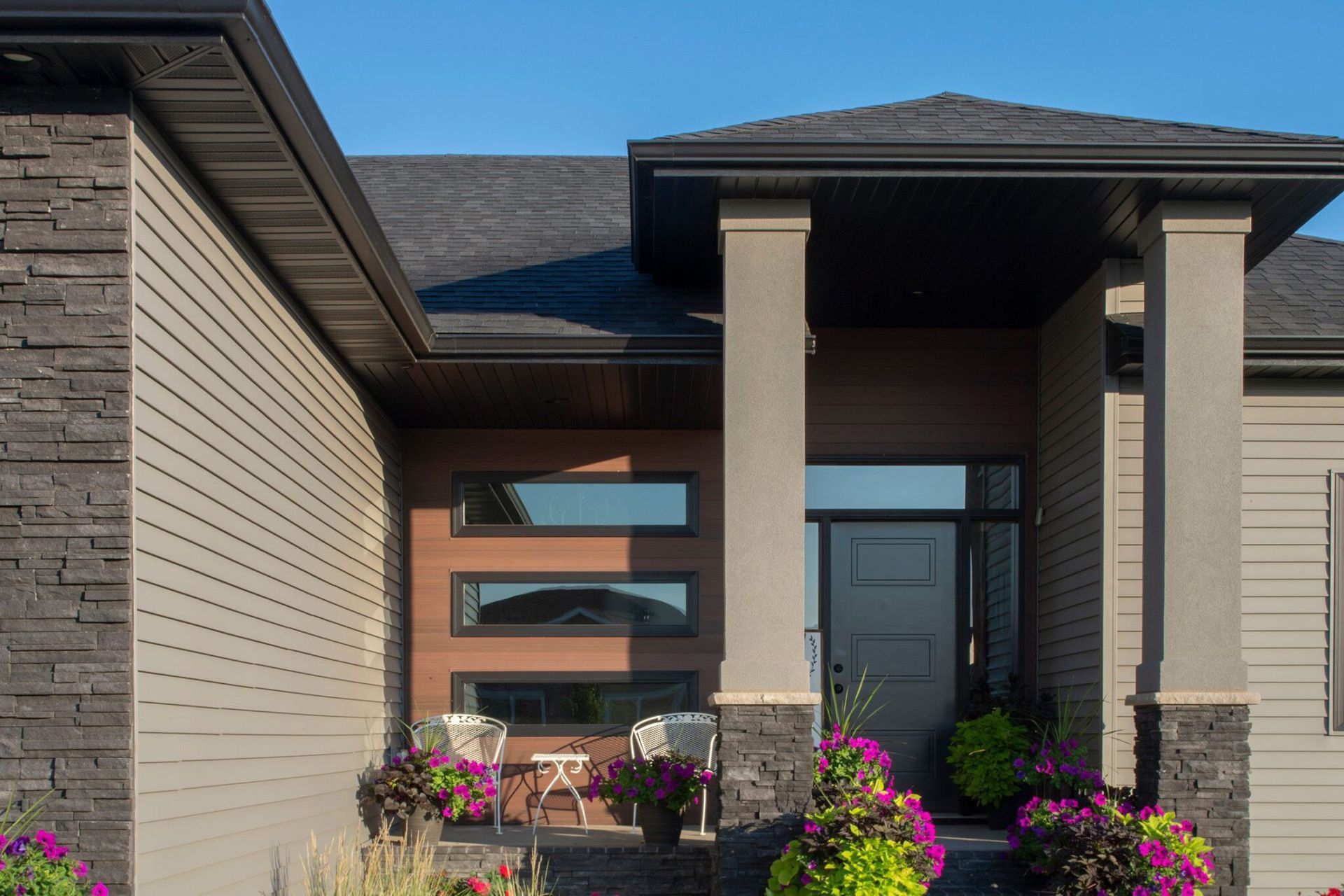 Modern house with a deck over a stream, surrounded by trees.